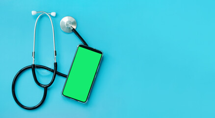 Stethoscope on a blue background and a smartphone with a green screen, top view. Cardiology and healthcare concept. Auscultation device. Chromatic mobile phone mockup. Online medical help concept