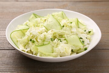 Tasty salad with Chinese cabbage, cucumber and green onion in bowl on wooden table, closeup