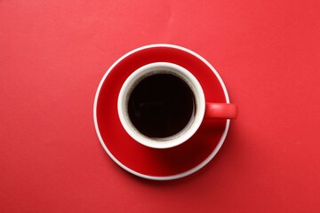 Obraz na płótnie Canvas Aromatic coffee in cup on red background, top view