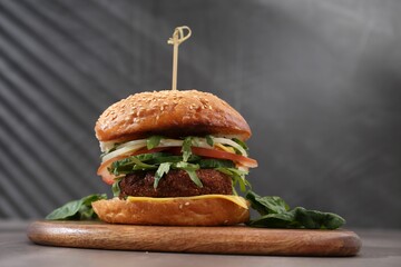 Board with delicious vegetarian burger on grey table