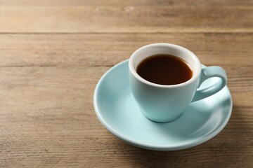 Tasty coffee in cup on wooden table, closeup. Space for text