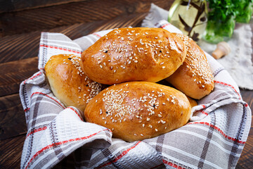 Delicious cabbage pies on wooden background. Baked homemade pirozhki with cabbage