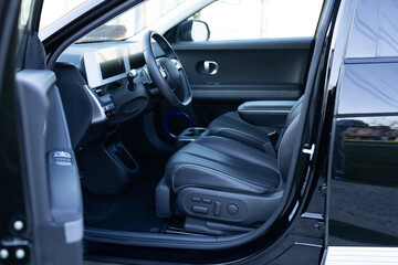 Electric car interior luxury inside. Steering wheel, dashboard, speedometer, display. Black leather...