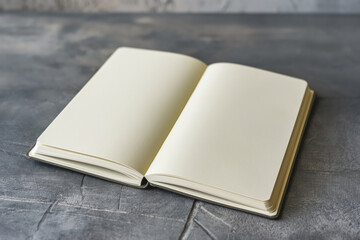 Fototapeta premium Open plain notebook with blank pages lays on a gray, textured surface, exemplifying simplicity and space for creativity