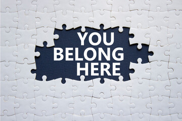 You belong here symbol. White puzzle with words You belong here. Beautiful deep blue background....