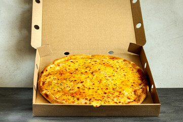 Hot cheese pizza in an open cardboard box. Selective focus