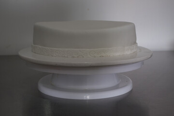 A white cake with a white ribbon on top of a white cake stand emptiness blank fresh start
