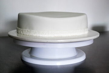 A white cake with a white ribbon on top of a white cake stand emptiness blank fresh start