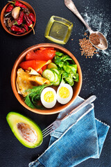Delicious healthy brunch - boiled egg, smoked salmon, green salad and savory pancakes on a dark background, top view - 786627005