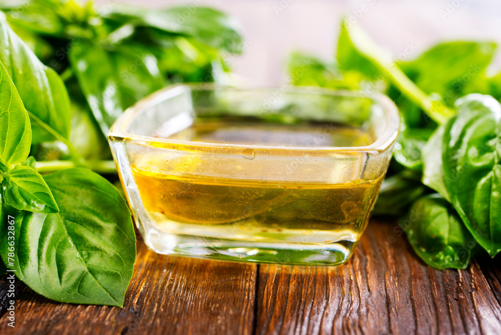 Wall mural Basil oil and fresh herbs on wooden table