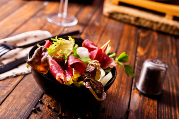 salad with jamon and red wine on wooden table - 786633095