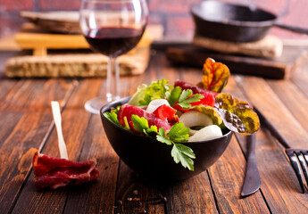 salad with jamon and red wine on wooden table
