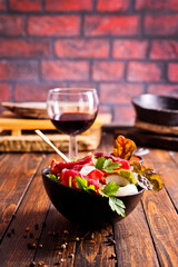 salad with jamon and red wine on wooden table - 786633421