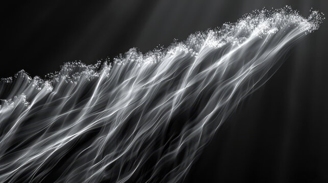   A monochrome image of a white light wave cresting atop a mid-ocean water wave