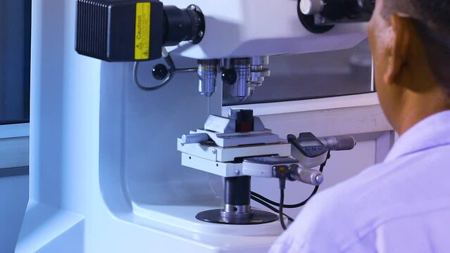 microscopic analysis of a metal part component under an advanced hi tech microscope by a scientist in a laboratory. quality control process in forging and machining factory foundry. iron alloy