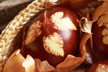 Close up of a brown Easter egg dyed with onion peels with a pattern of leaves in a basket
