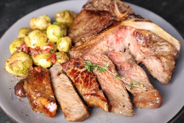 Delicious fried beef meat, vegetables and thyme on plate, closeup