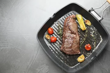 Fotobehang Delicious grilled beef meat and vegetables in pan on grey table, top view. Space for text © New Africa