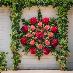 A wall featuring an arrangement of red and pink flowers in its center