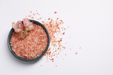 Natural sea salt and flowers in bowl on white background, top view. Space for text