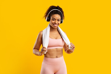 Cheerful african american lady with headphones and towel - obrazy, fototapety, plakaty