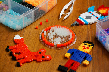 Colorful iron beads (perler beads or iron beads) in a box, art toys created from them and white...