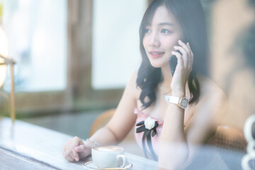 Portrait of beautiful happy Smiling asian woman relaxing and and smartphone sitting in cafe...