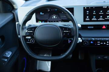 Obraz na płótnie Canvas Steering wheel of electric vehicle, interior, cockpit, electric buttons. Autonomous car. Driverless car. Self-driving vehicle. Empty cockpit electric vehicle, Head Up Display and digital speedometer