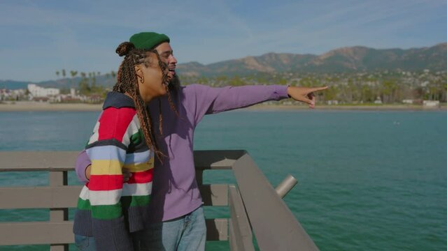 Perfect holidays of young happy African American couple by the ocean, black man and black woman gazing at breathtaking views of blue waters, shoreline and mountains. High quality 4k footage