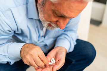 Middle aged senior man holding medical pills. Mature old senior grandfather taking medication cure...