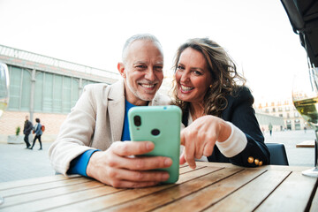 Middle aged couple having fun sharing media with a cellphone. Mature people watching the smartphone...