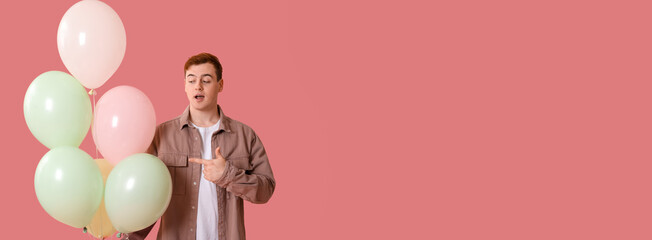 Young man with air balloons celebrating Birthday on pink background