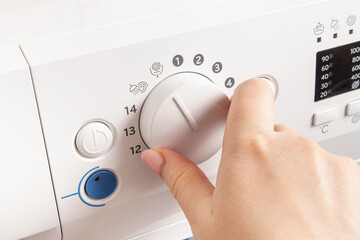 Woman switches washing modes on a washing machine. Rinsing and wringing of laundry