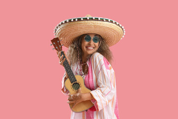 Mature woman in sombrero hat playing guitar on pink background. Mexico's Day of the Dead (El Dia de...