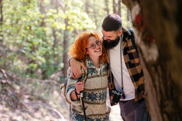 A beautiful and cheerful couple is hiking in the forest enjoying nature and each other's company - 786664459