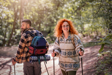 A beautiful and cheerful couple is hiking in the forest enjoying nature and each other's company