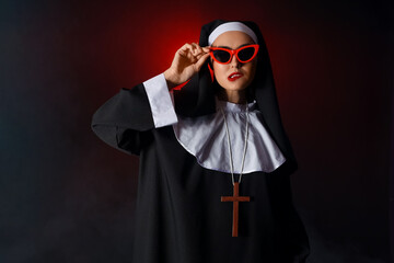 Naughty nun in sunglasses on dark background
