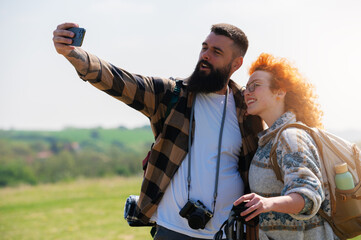 A beautiful and cheerful hiking couple captures a selfie with a stunning landscape in the background - 786667050