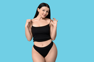 Body positive young woman in underwear on blue background