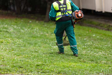 Worker using a weed trimmer in a park