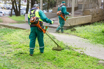 Workers mowing lawn in urban setting