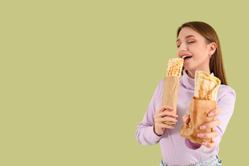 Young woman with doner kebabs on green background