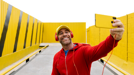 Smiling man taking selfie with yellow backdrop