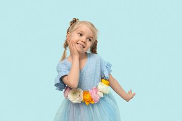 Happy little girl with beautiful ranunculus flowers on blue background