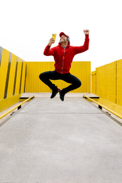 Joyful man taking a selfie while jumping in urban space