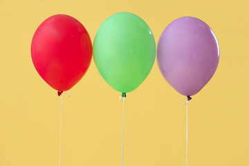 Colorful floating balloons on yellow background