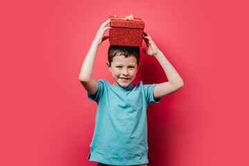 Young boy holding a red glittery gift box overhead