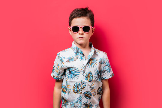 Young boy showcases summer fashion on pink backdrop