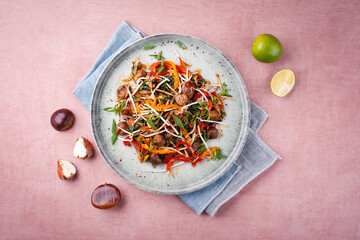 Traditional Asian wok spinach with chestnuts, pepper strips and soy sprouts served as top view in a...