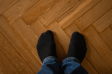 male legs in black socks on wooden parquet, top view, place for writing